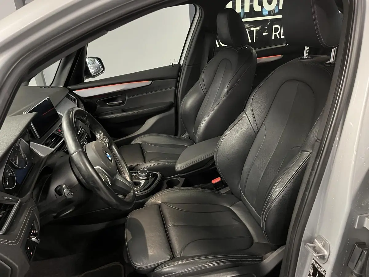 Vue intérieure côté conducteur de la BMW Série 2 225xe Active Tourer gris, sièges cuir noirs et tableau de bord moderne.