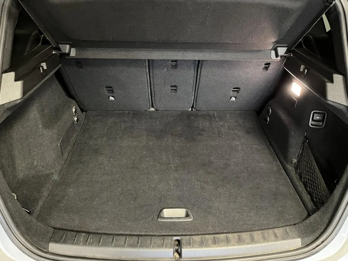Coffre ouvert vu de face, intérieur noir avec éclairage latéral et filet de rangement sur la droite.