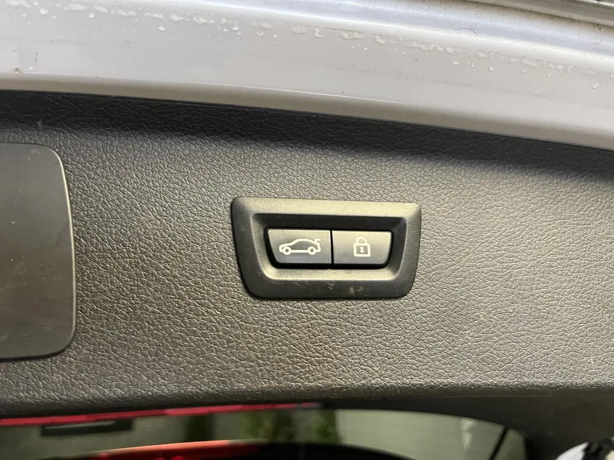 Boutons d'ouverture et de verrouillage du hayon sur la garniture intérieure d'un coffre de BMW Série 2 gris.