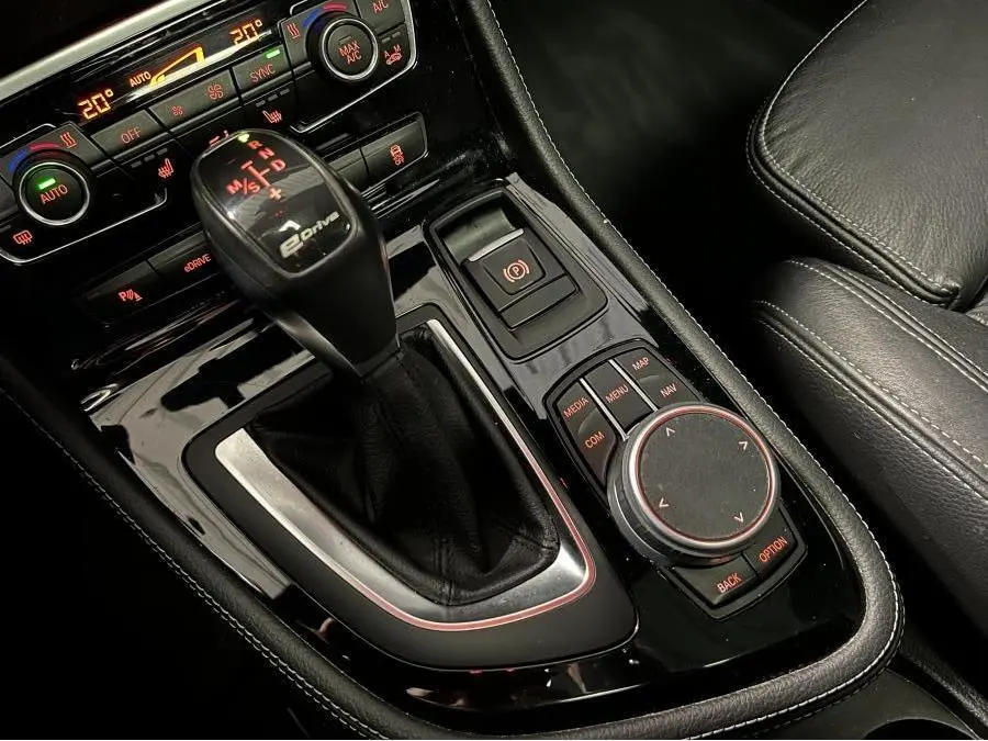 Gros plan sur la console centrale noire de la BMW Série 2 225xe M Sport avec levier de vitesse eDrive et commandes multimédia.