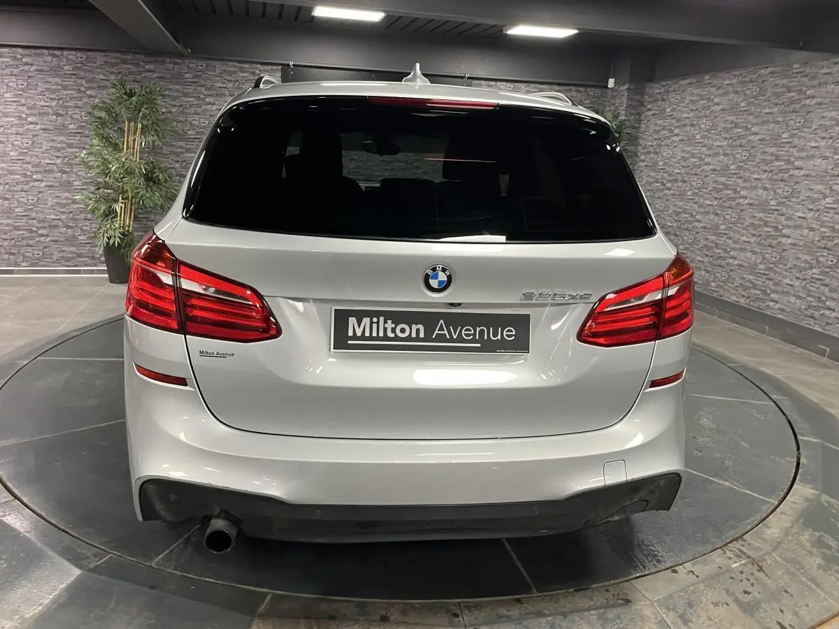 Vue arrière d'une BMW Série 2 225xe Active Tourer gris métallisé avec feux rouges et hayon fermé en intérieur.