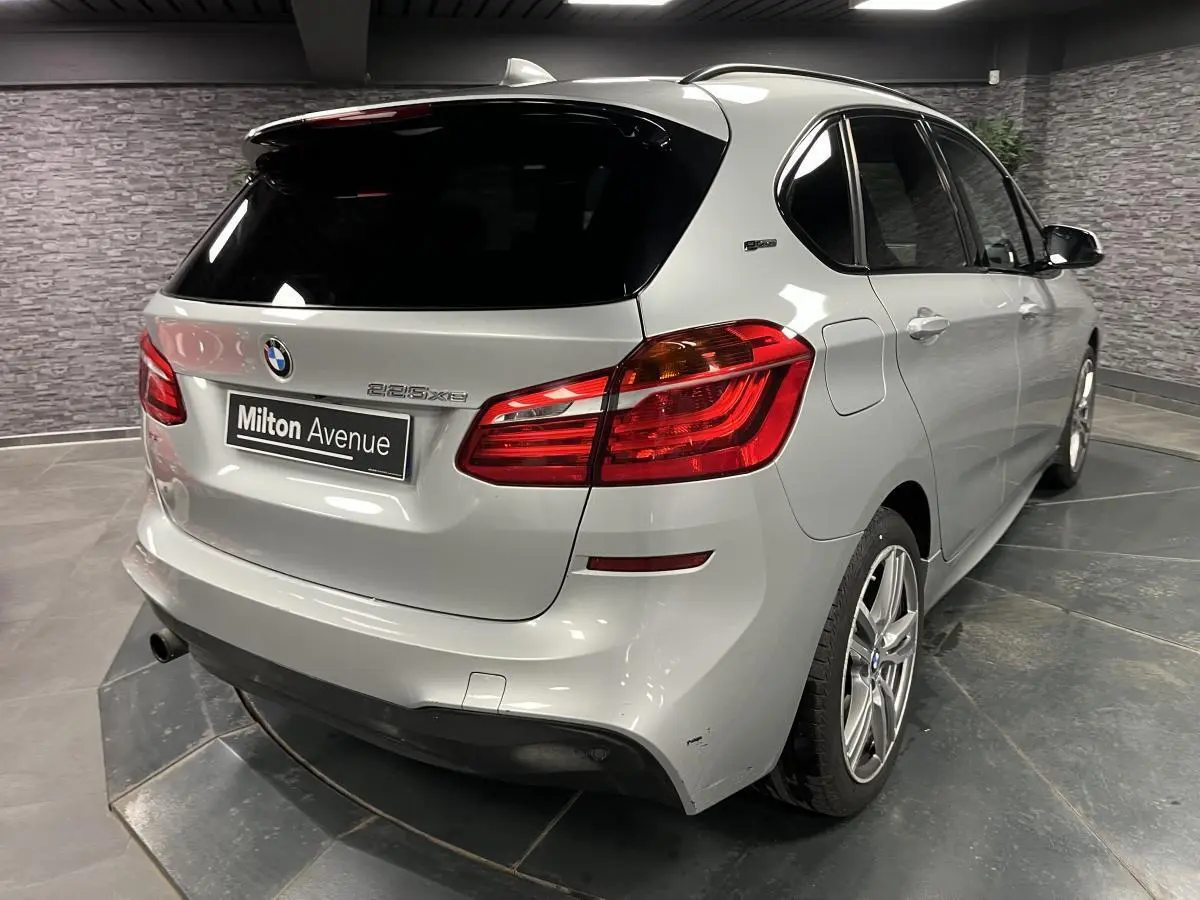 Vue 3/4 arrière droite d'une BMW Série 2 225xe Active Tourer gris métallisé avec jantes alliage et toit noir.