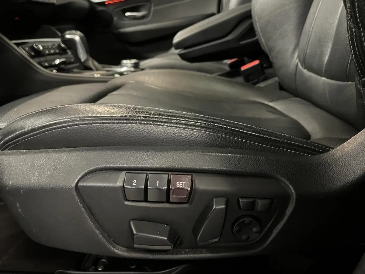 Détail des commandes électriques de réglage du siège conducteur en cuir noir dans une BMW Série 2 225xe Active Tourer.