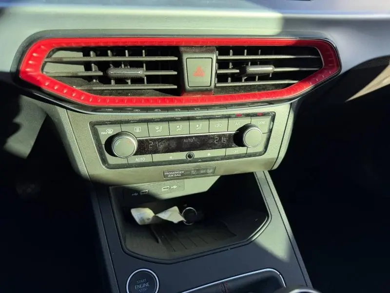 Vue rapprochée de la console centrale de la SEAT Ibiza 2025, avec cadre d'aération rouge et commandes de climatisation.