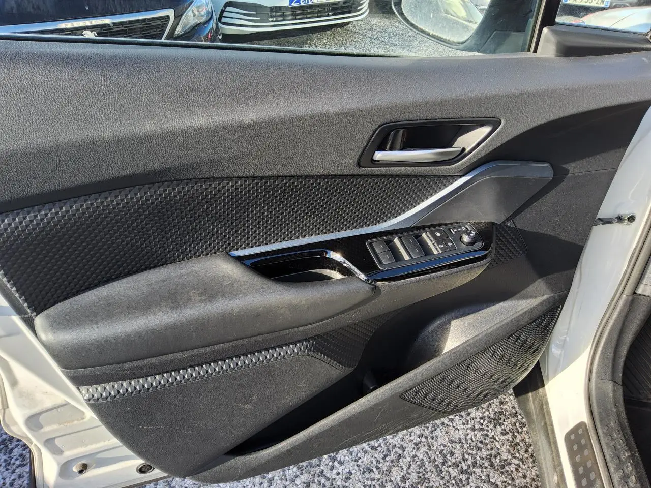 Vue côté gauche de la porte avant blanche nacrée du Toyota C-HR 2020 avec commandes électriques et garnitures noires texturées.