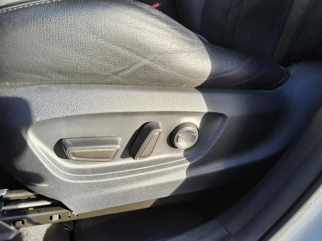 Détail des commandes de réglage manuel du siège conducteur en cuir noir dans un Toyota C-HR blanc nacré 2020.