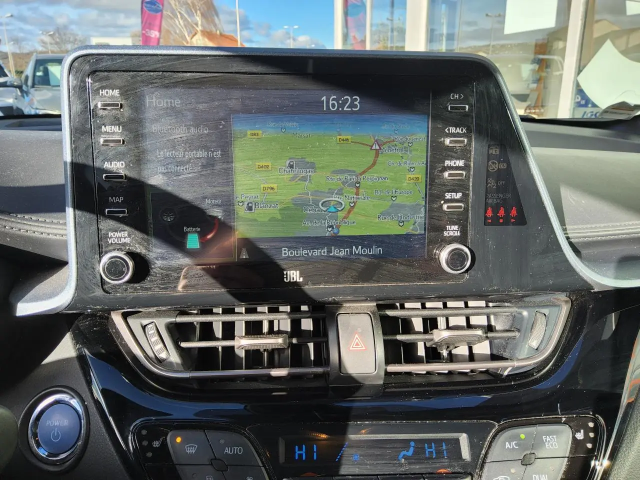Vue rapprochée de la console centrale du Toyota C-HR blanc nacré, avec écran tactile de navigation et commandes climatisation.