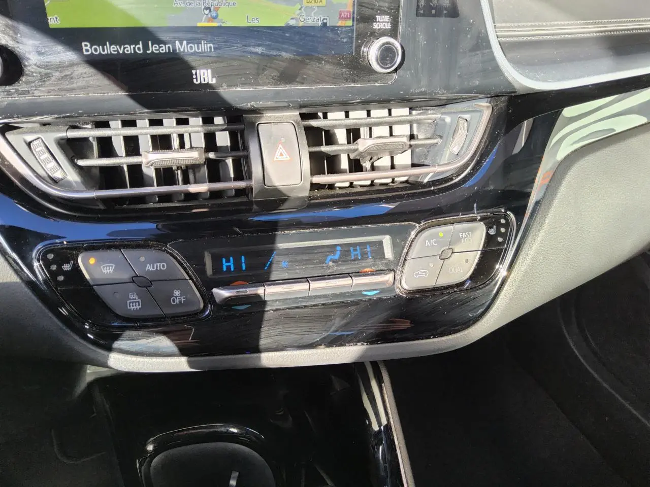Vue rapprochée de la console centrale noire brillante du Toyota C-HR 2.0 Hybrid 2020 avec commandes climatisation digitale.