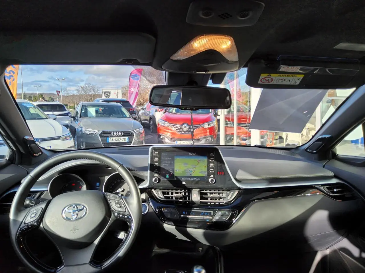 Vue intérieure avant du Toyota C-HR blanc nacré 2020, avec tableau de bord moderne et écran tactile central allumé.
