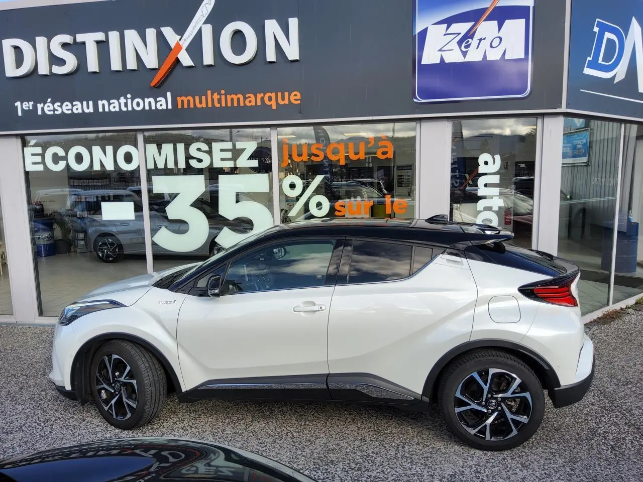 Toyota C-HR blanc nacré vue de profil côté gauche avec toit noir et jantes alliage 18 pouces.