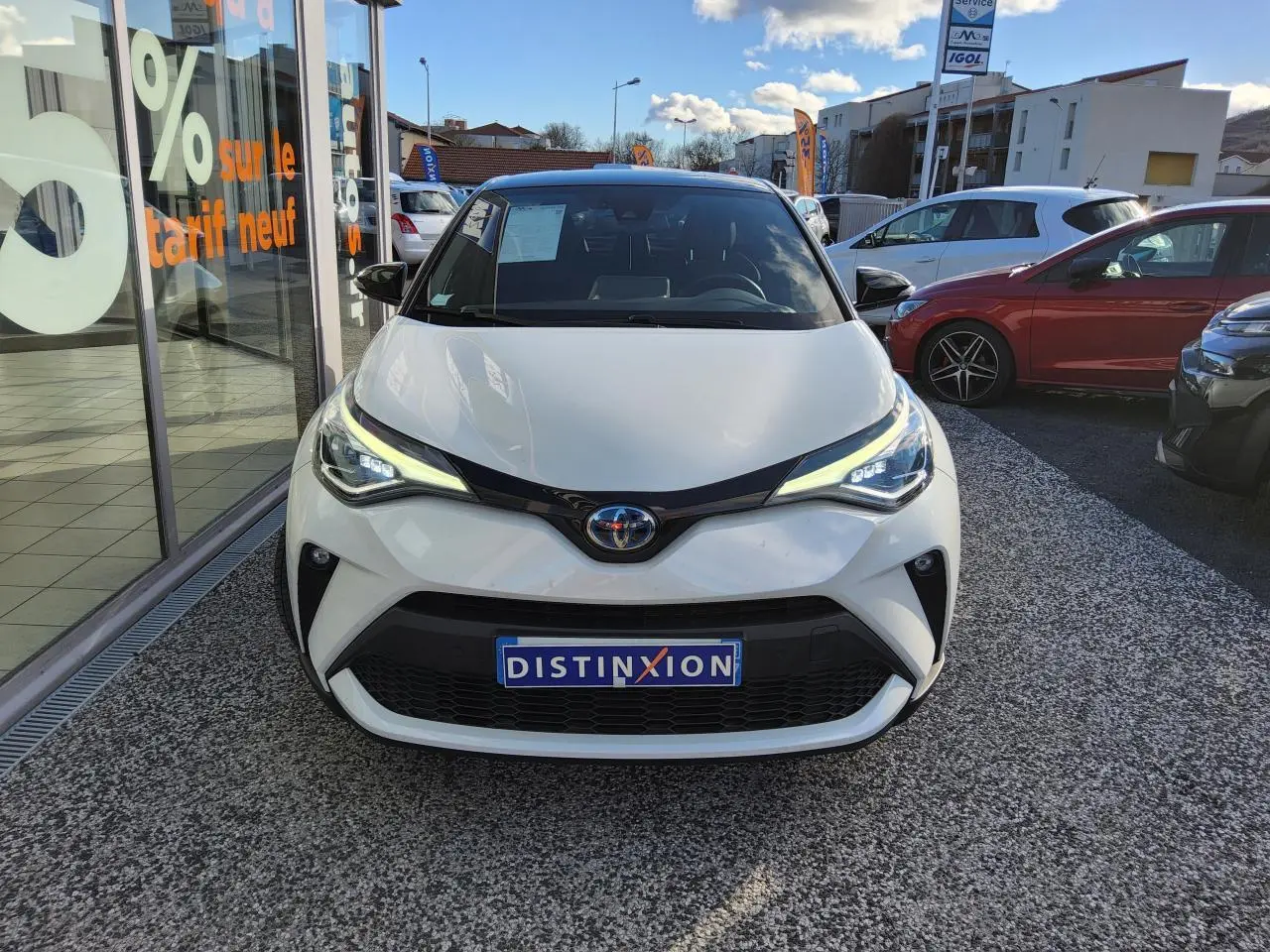 Vue avant d'une Toyota C-HR 2.0 Hybrid blanc nacré avec calandre noire et phares LED allumés.