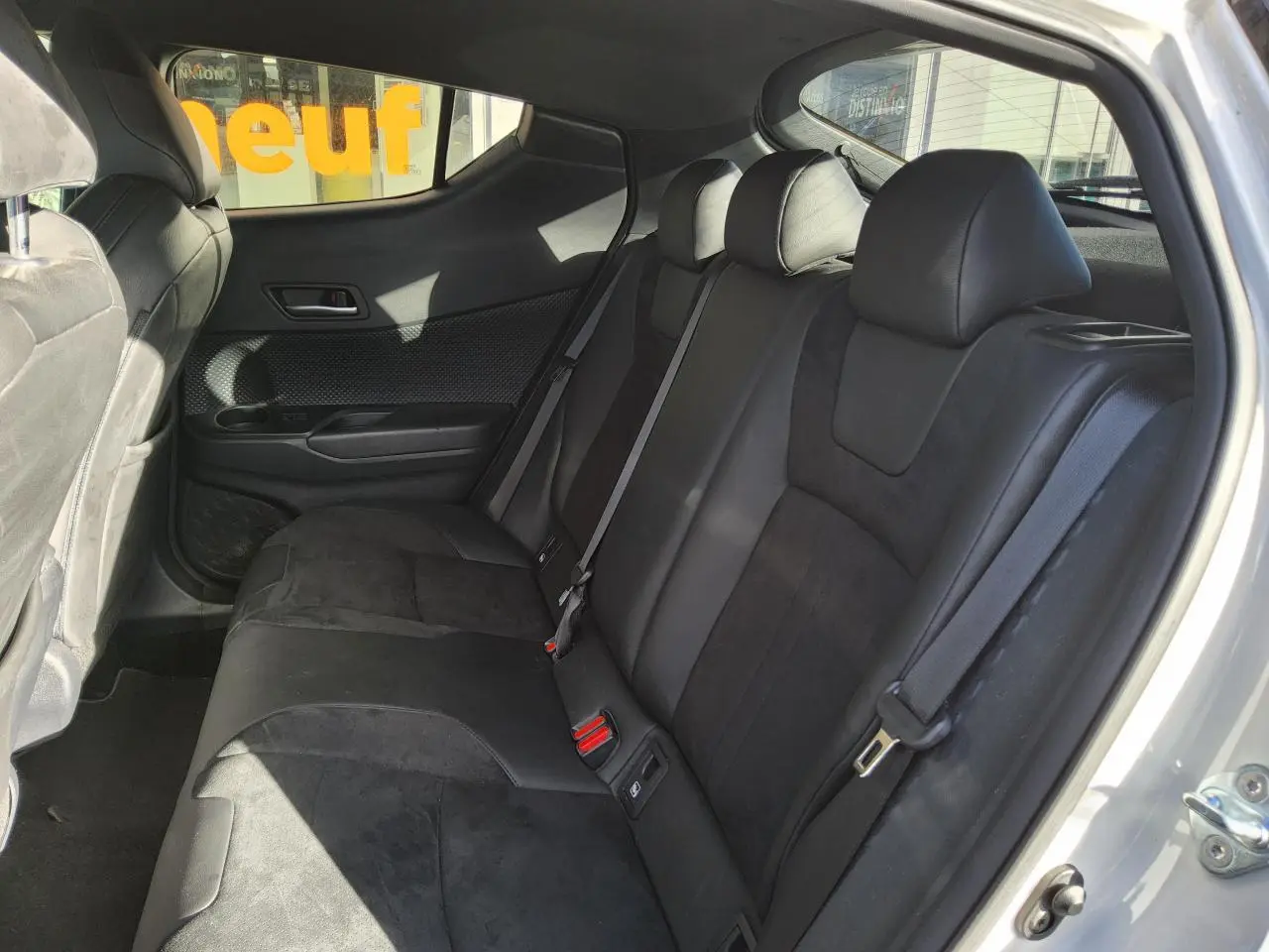 Vue intérieure côté arrière droit du Toyota C-HR blanc nacré 2020, montrant les sièges arrière en tissu noir et alcantara.