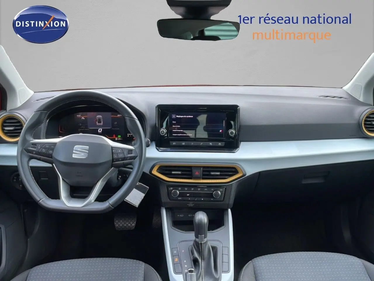 Vue intérieure frontale du tableau de bord du SEAT Arona rouge Désir Métal 2025 avec volant multifonction et écran tactile central.