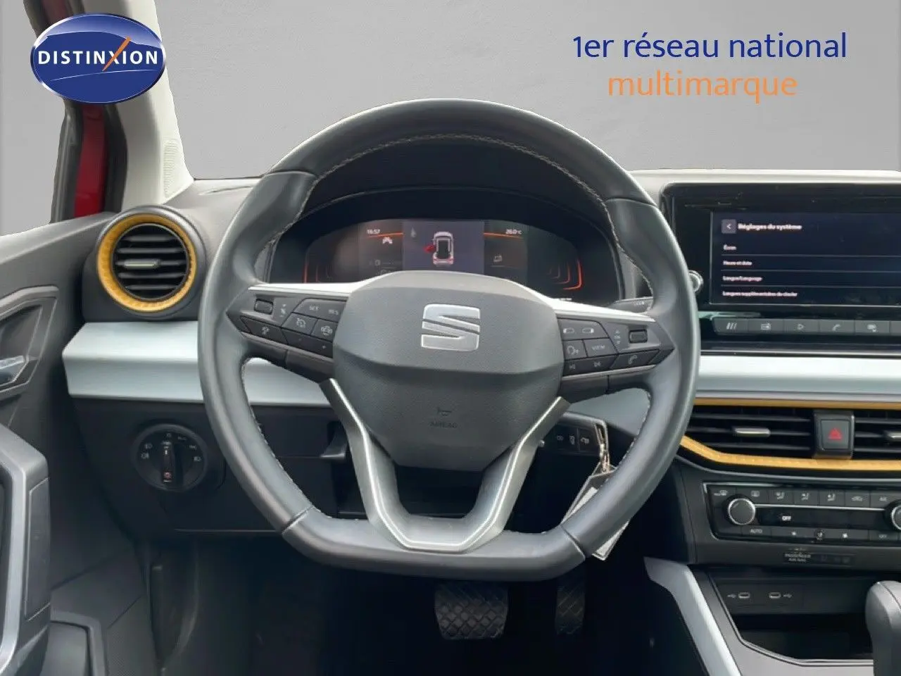 Vue intérieure centrée sur le volant cuir du SEAT Arona 2025, avec tableau de bord et détails jaunes autour des aérateurs.