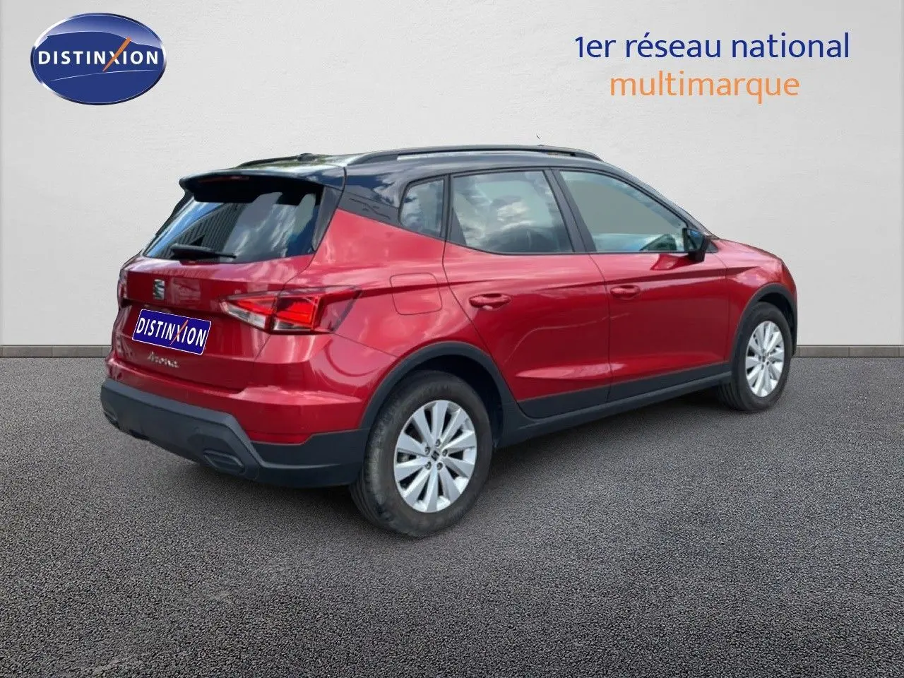 Vue 3/4 arrière droite d’un SEAT Arona rouge désir métal avec toit noir, jantes argent et détails noirs contrastants.