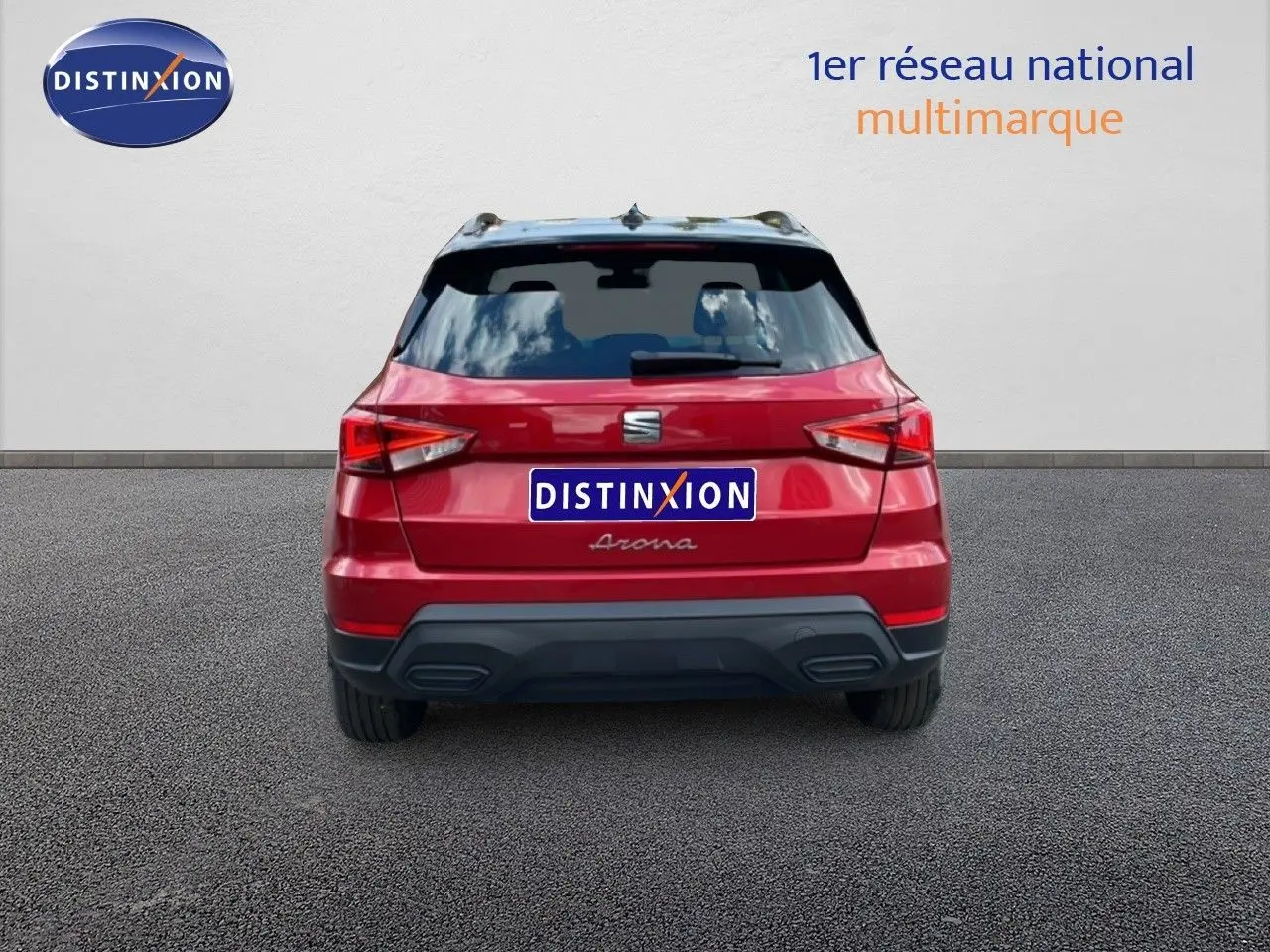 Vue arrière d'un SEAT Arona rouge Désir Métal avec toit noir, en stationnement devant un mur blanc.