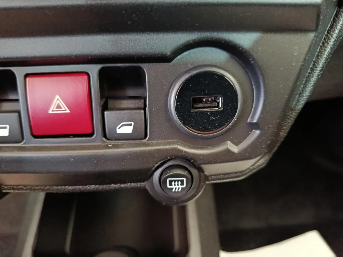 Gros plan sur la console centrale de l'AIXAM Ambition 0.5 City Coupe GTI noire, montrant les boutons de commande et un port USB.