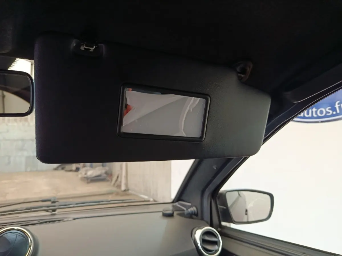 Vue intérieure du pare-soleil côté conducteur de l'Aixam Ambition 0.5 City Coupe GTI noir avec rétroviseur extérieur visible.