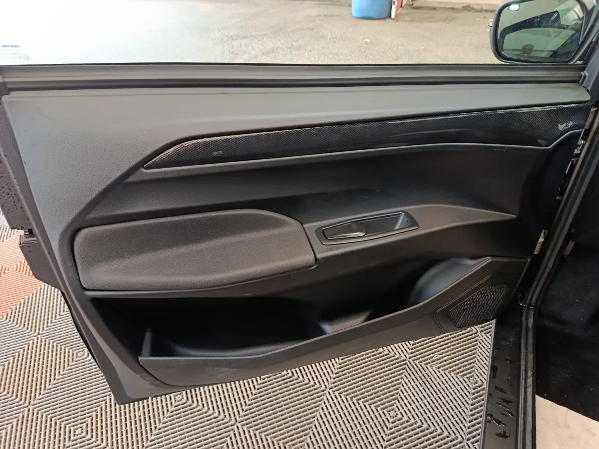 Vue intérieure de la porte côté conducteur de l'AIXAM Ambition 0.5 City Coupe GTI noire, avec poignée et rangements intégrés.