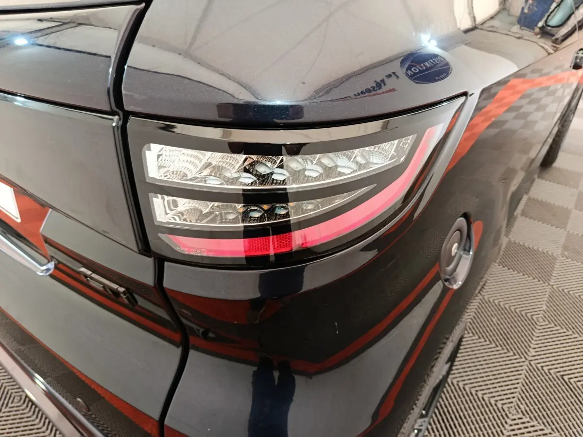 Gros plan sur le feu arrière droit noir brillant de l'AIXAM Ambition 0.5 City Coupe GTI 2026 avec réservoir visible.