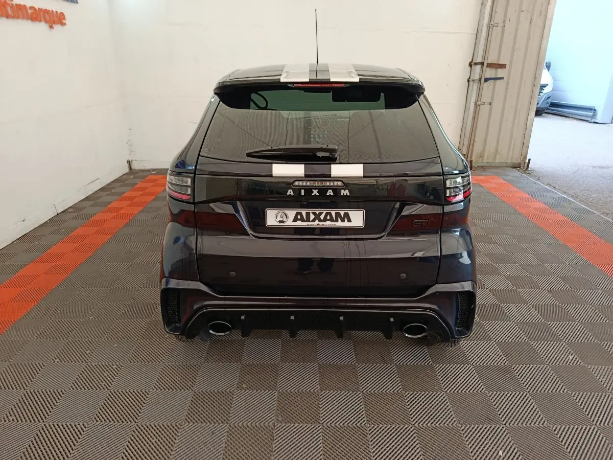 Vue arrière d'une Aixam Ambition 0.5 City Coupe GTI noire avec bandes blanches et double sortie d'échappement.