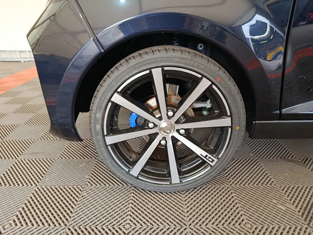 Gros plan sur la roue arrière droite noire de l'AIXAM AMBITION 0.5 CITY COUPE GTI avec jante alu bicolore et logo GTI.