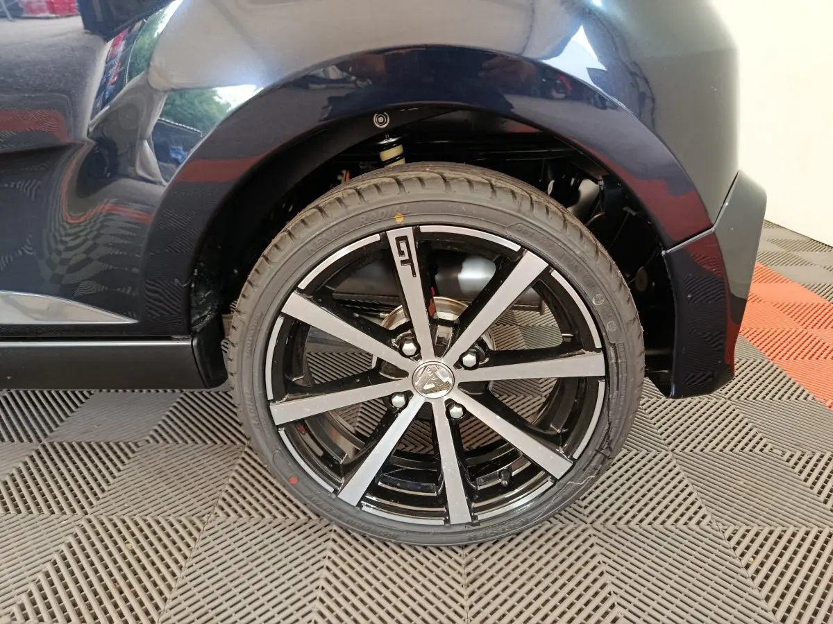 Gros plan sur la roue arrière droite noire de l'AIXAM AMBITION 0.5 CITY COUPE GTI 2026 avec jante noire et argent.