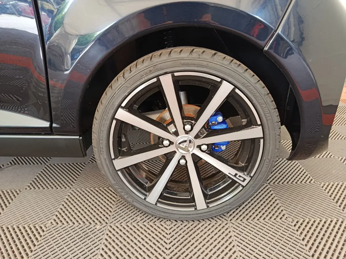 Gros plan sur la roue avant droite noire d'une Aixam Ambition 0.5 City Coupe GTI avec étrier de frein bleu.