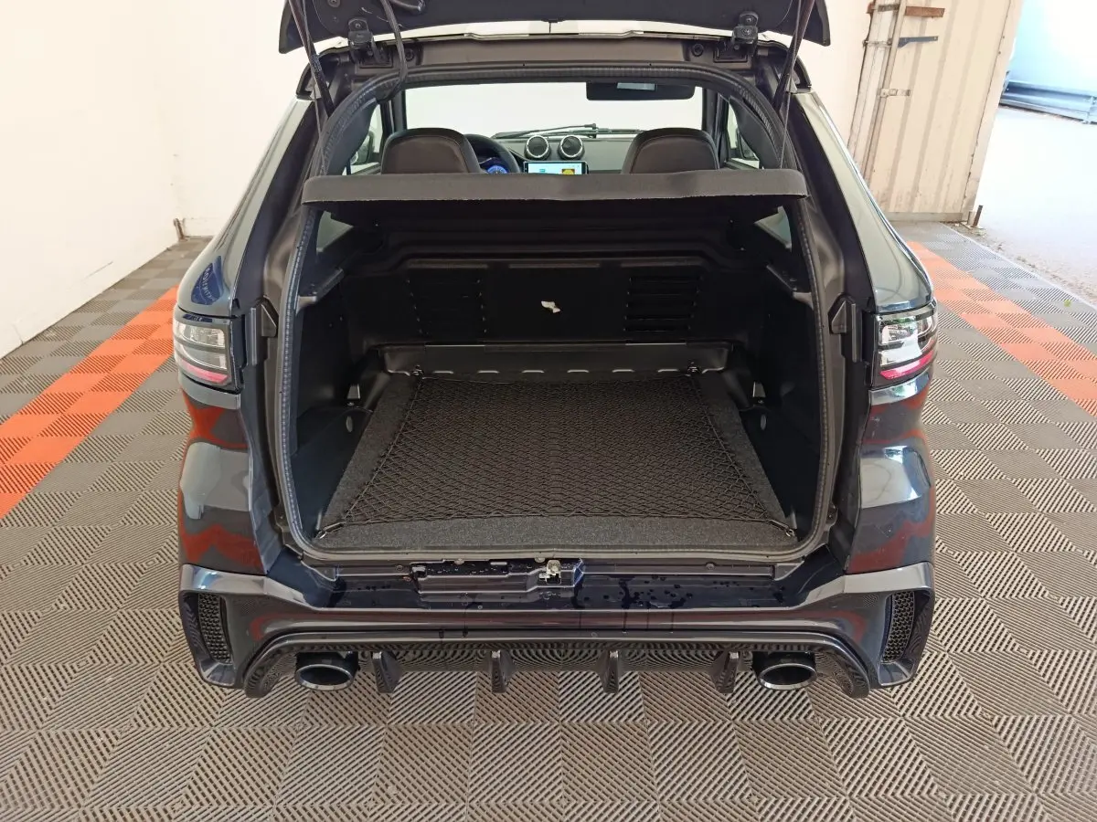 Coffre ouvert vu de l'arrière d'une AIXAM Ambition 0.5 City Coupe GTI noire avec double sortie d'échappement.