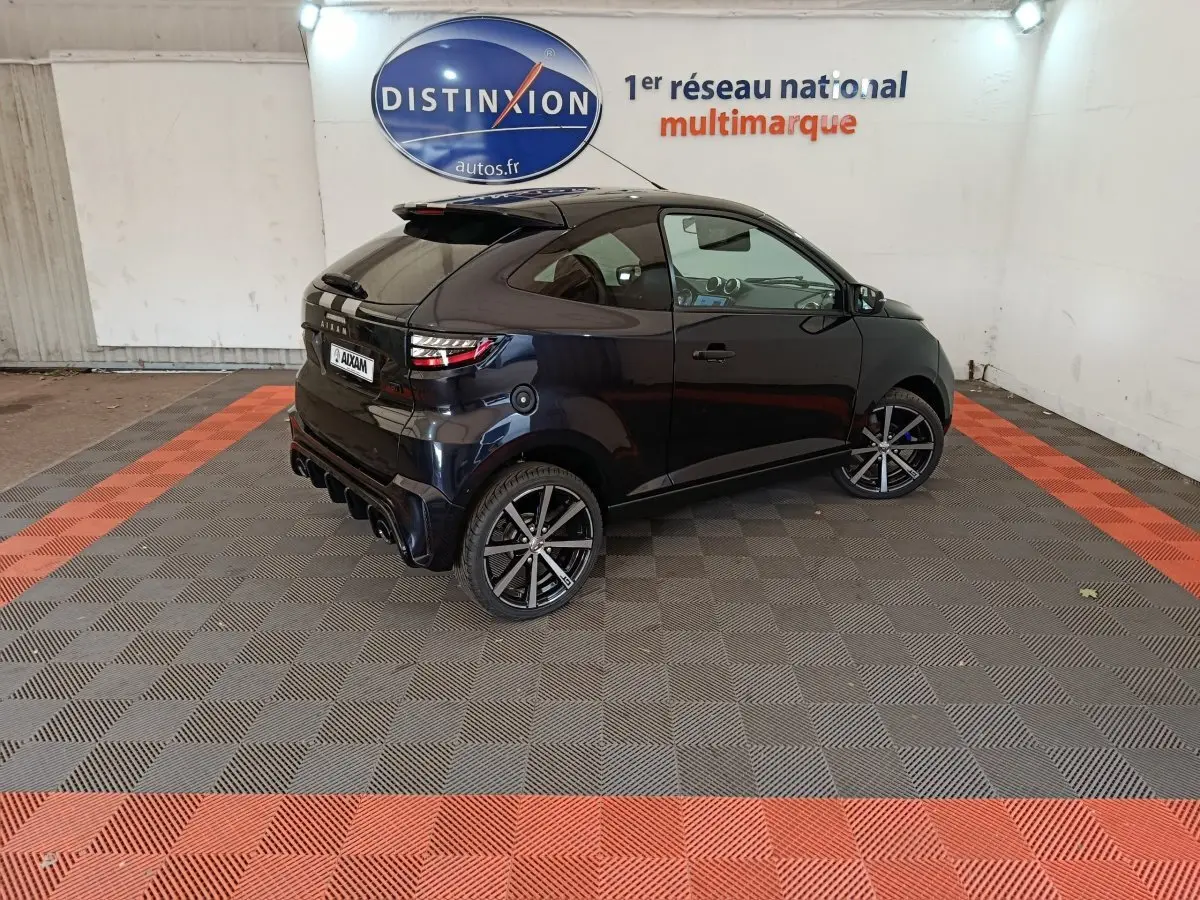 Vue 3/4 arrière droite d'une Aixam Ambition 0.5 City Coupe GTI noire avec jantes sport et rétroviseur côté conducteur.