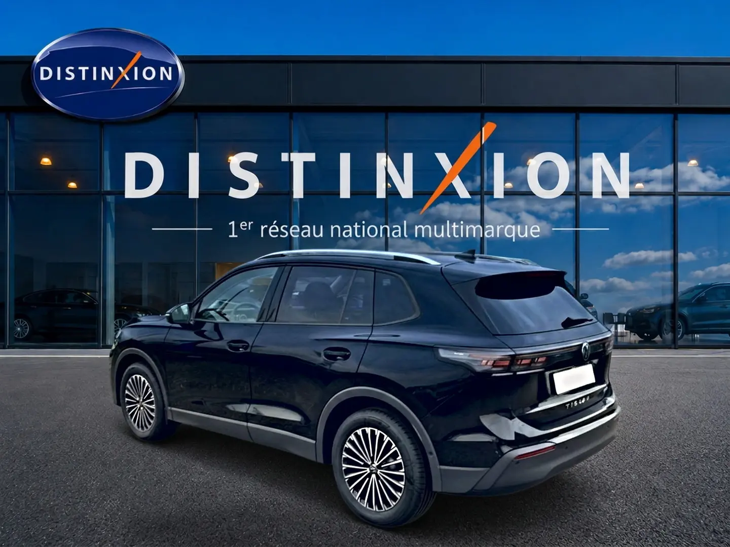 Volkswagen Tiguan 1.5 eTSI noir vue 3/4 arrière droit avec barres de toit argentées devant un showroom Distinxion.
