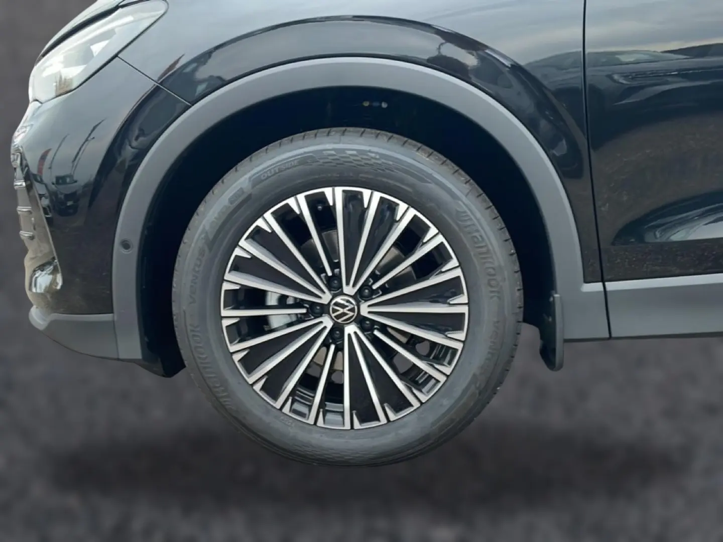 Gros plan sur la roue avant gauche du Volkswagen Tiguan noir 2025 avec jante alliage multibranches.