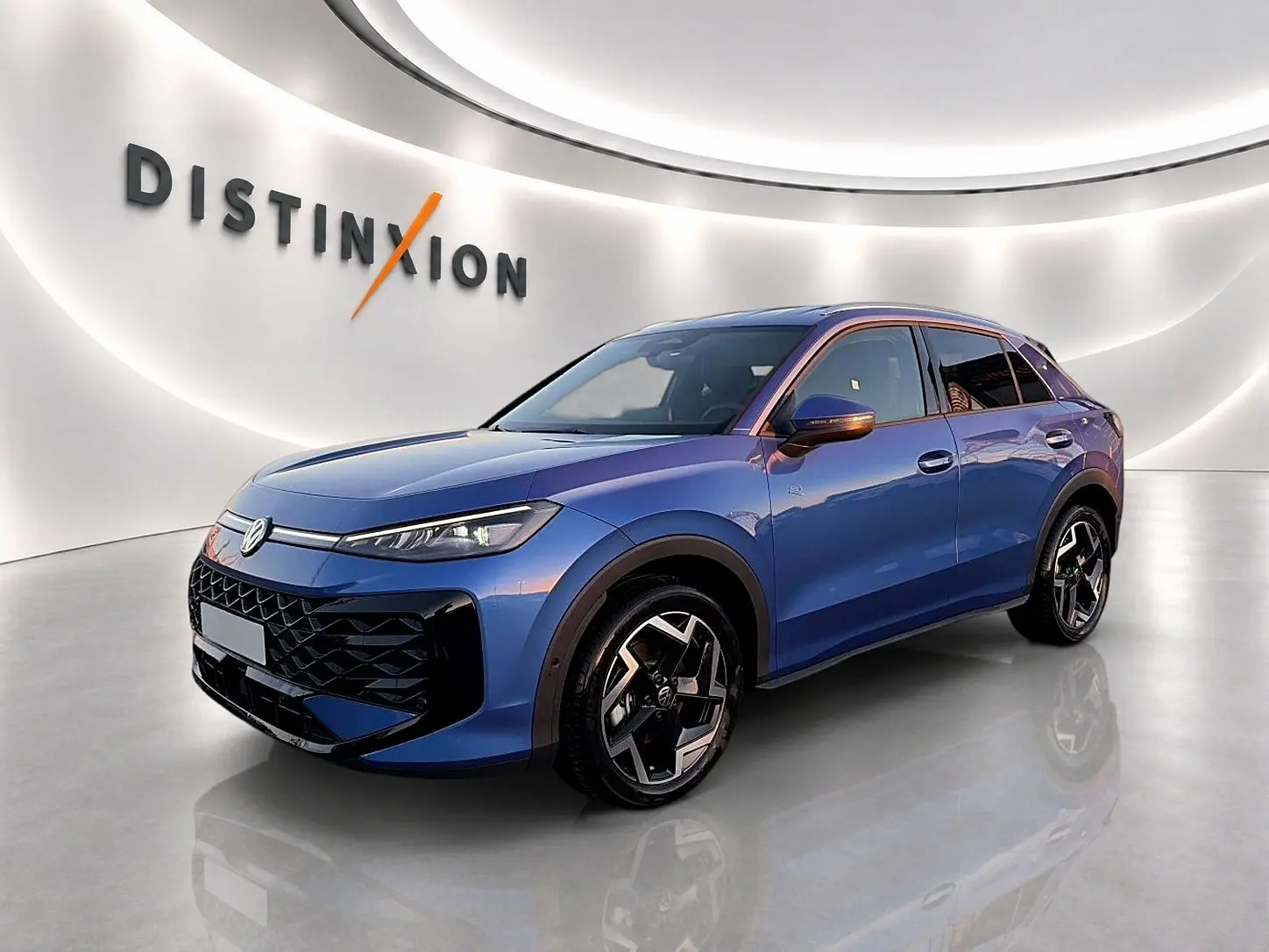 Volkswagen T-Roc 2026 bleu céleste en 3/4 avant droit, avec jantes alu noires et calandre noire distinctive.