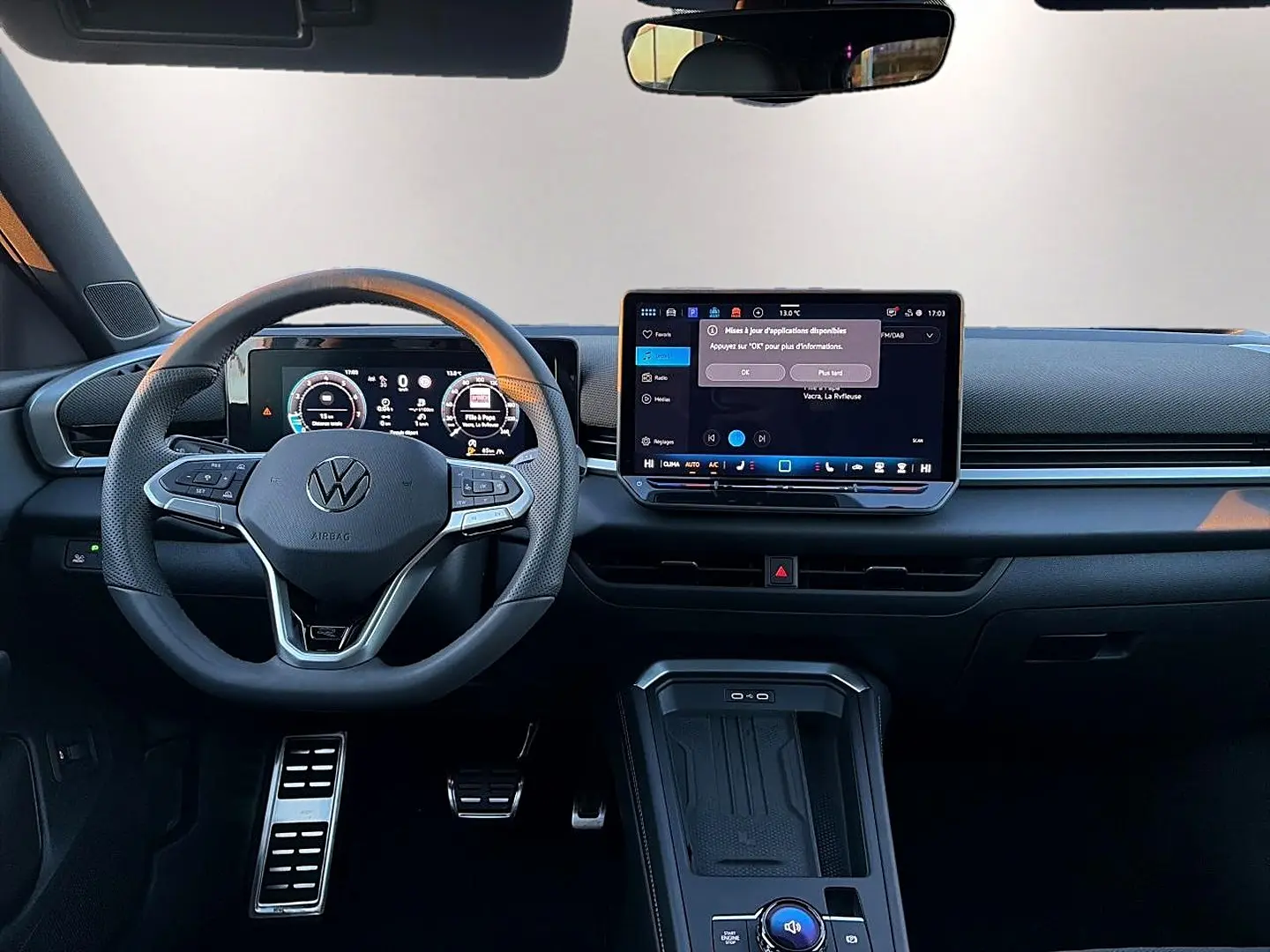 Vue intérieure frontale du tableau de bord noir du Volkswagen T-Roc 2026 avec volant cuir multifonction et écran tactile central.