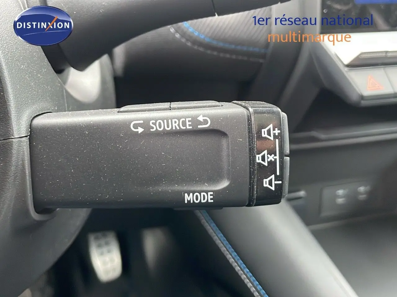 Gros plan sur la commande audio au volant du Renault Symbioz gris Rafale Métal, intérieur moderne avec surpiqûres bleues.