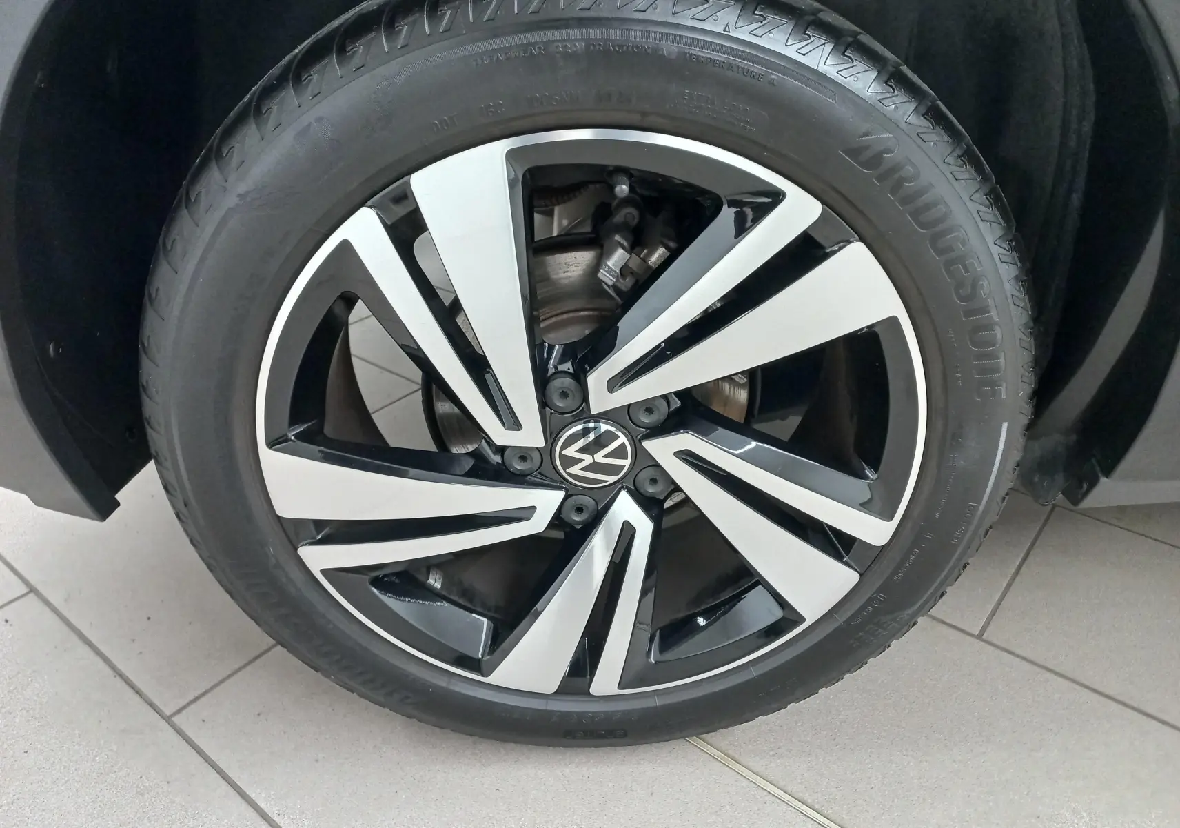 Gros plan sur la jante alliage bicolore noir et argent du Volkswagen T-Roc blanc pur, version R-Line 2025.