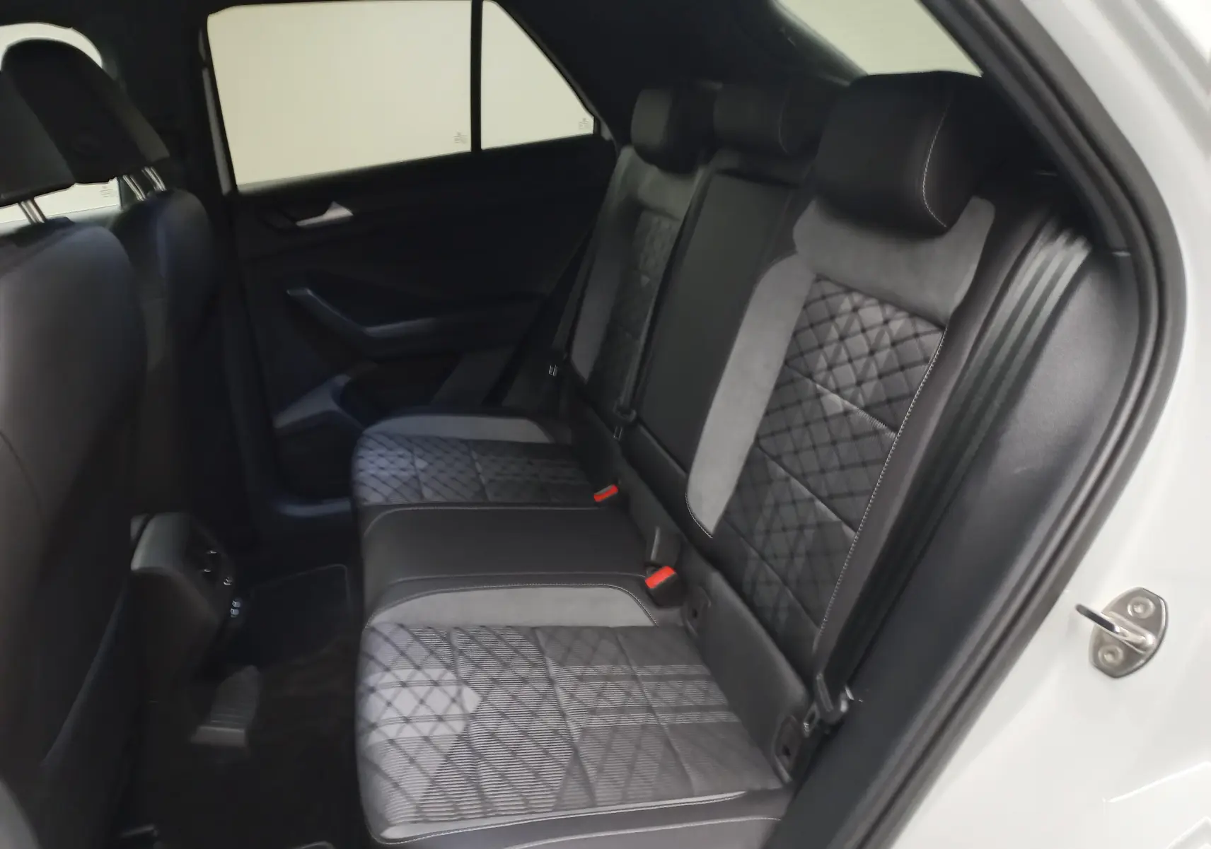 Vue intérieure côté droit des sièges arrière en cuir noir et tissu gris à motifs géométriques du Volkswagen T-Roc blanc pur 2025.
