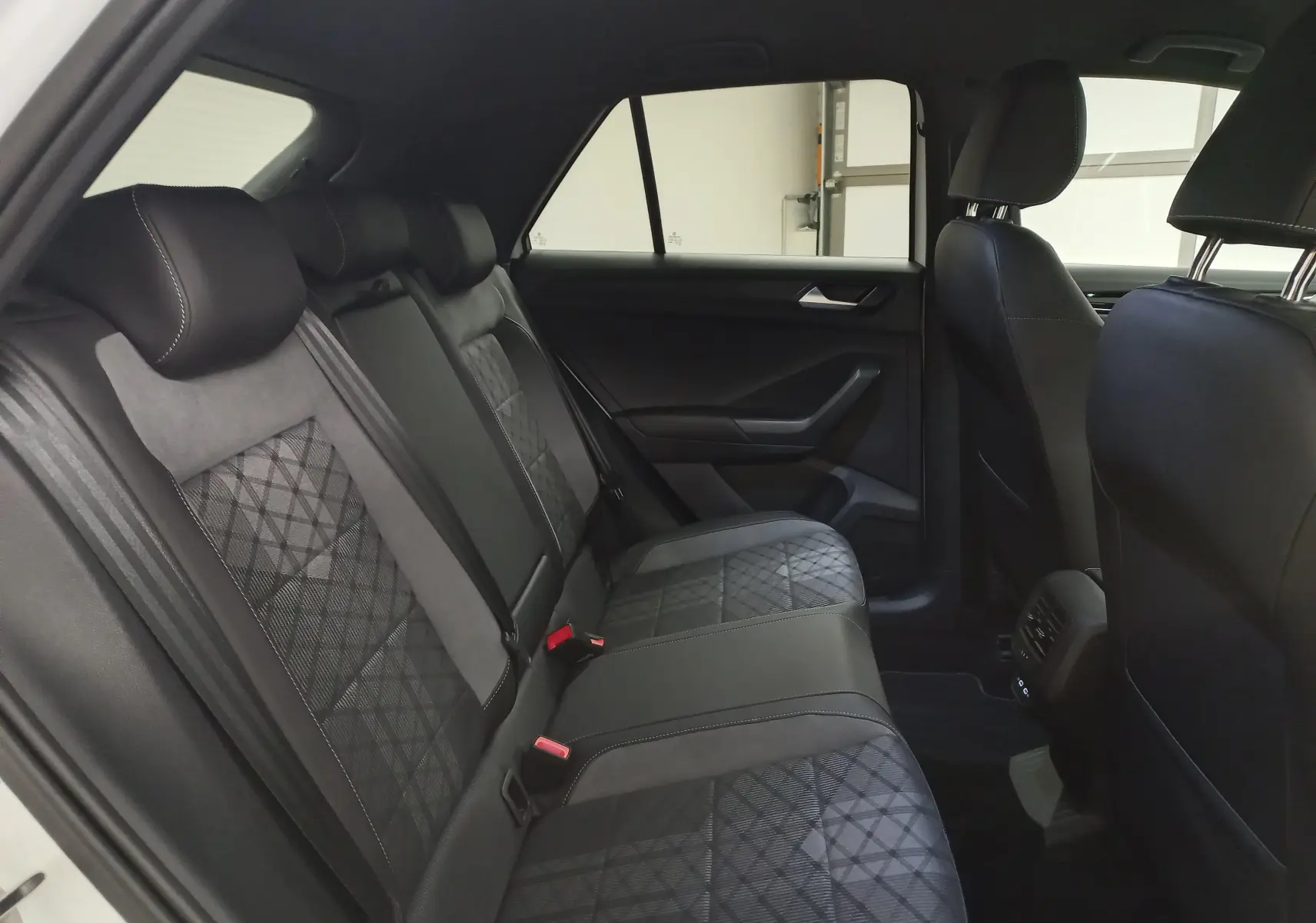 Vue intérieure côté gauche des sièges arrière du Volkswagen T-Roc 1.5 TSI R-Line Edition 2025 avec sellerie noire à motifs géométriques.