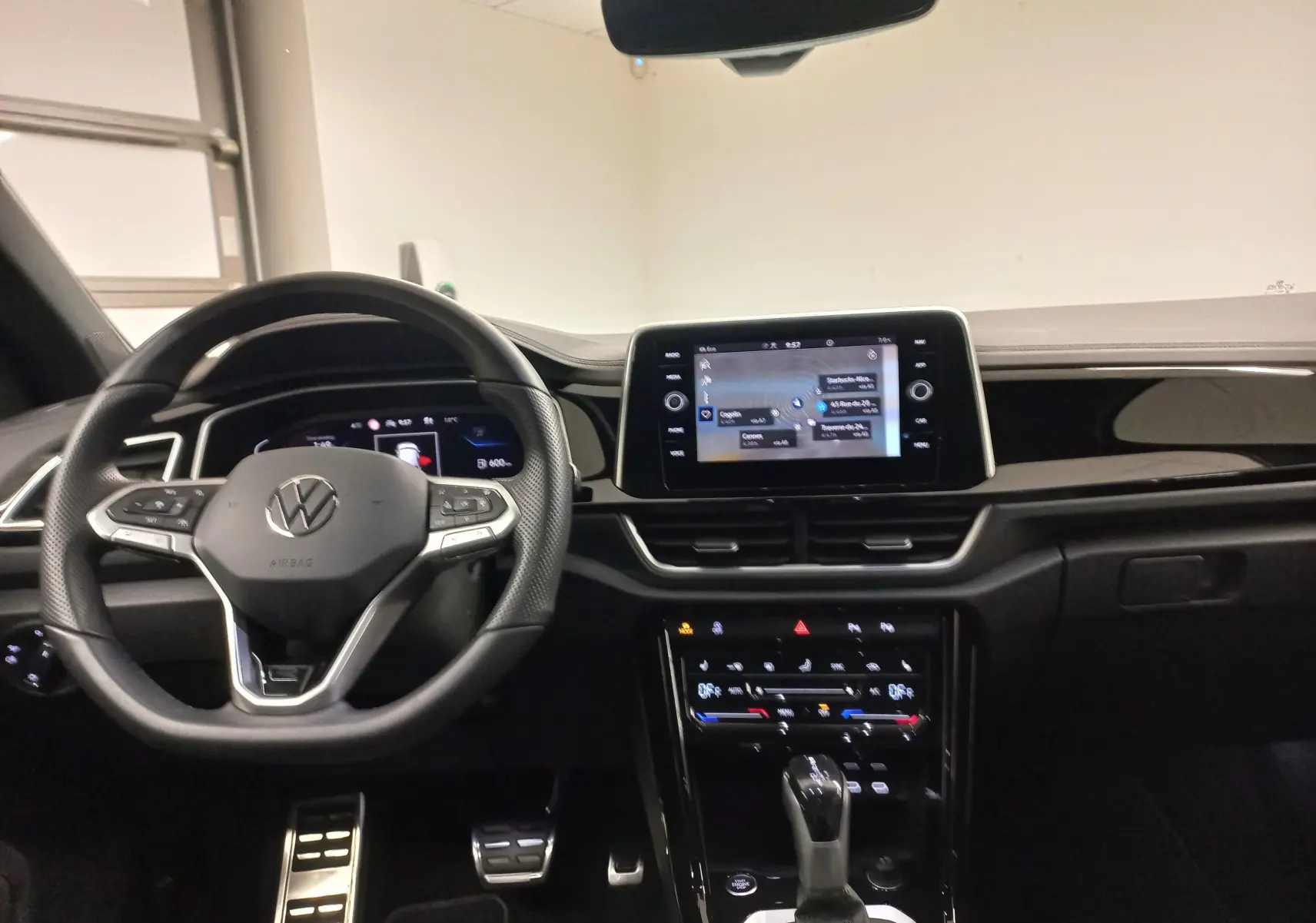 Intérieur du Volkswagen T-Roc 1.5 TSI blanc, vue du poste de conduite avec écran tactile central et volant multifonction.