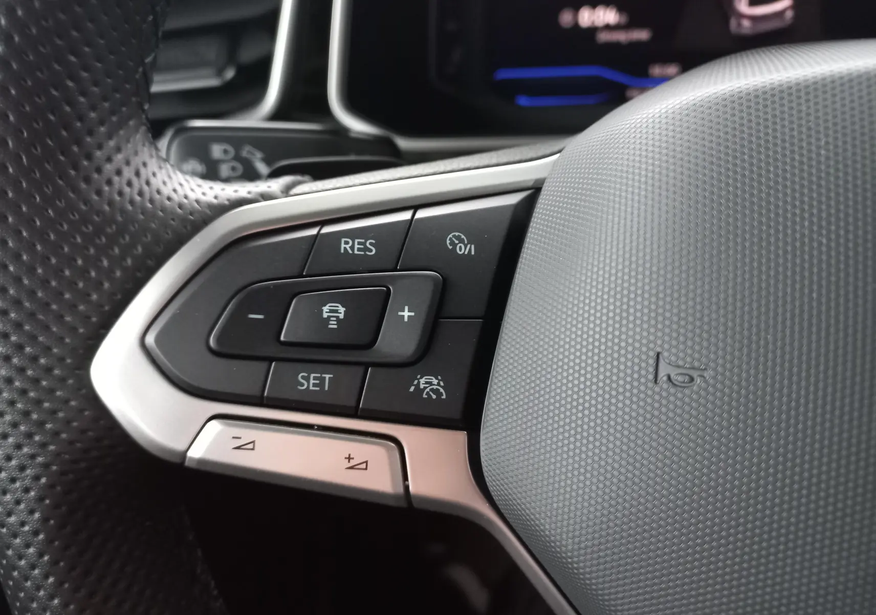 Gros plan sur les commandes du volant à gauche du Volkswagen T-Roc blanc pur, version R-Line 2025.