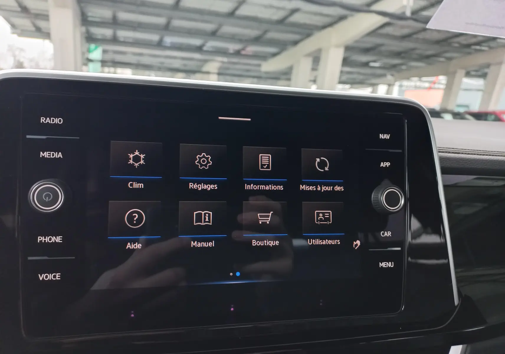 Écran tactile central du Volkswagen T-Roc blanc pur 2025, affichant le menu des réglages et options connectées.