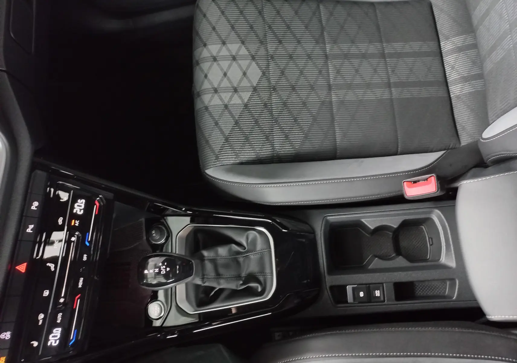 Vue plongeante sur la console centrale du Volkswagen T-Roc 1.5 TSI blanc, avec levier de vitesse DSG et siège tissu gris.