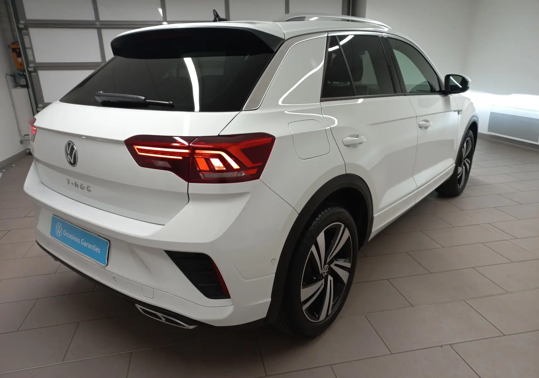 Volkswagen T-Roc blanc pur en 3/4 arrière droit, avec feux arrière LED et jantes alliage distinctives R-Line.