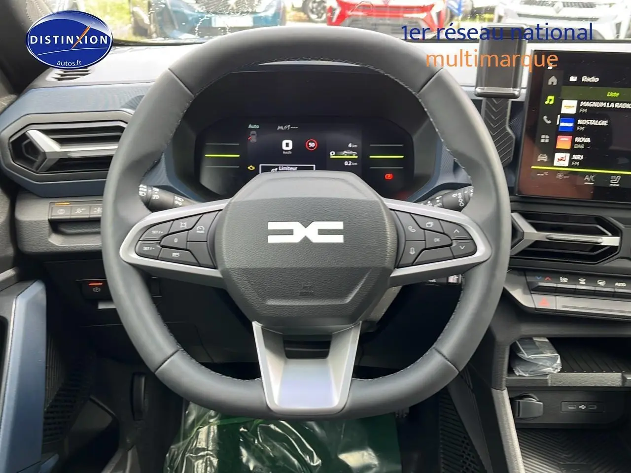 Vue intérieure centrée sur le volant multifonction du Dacia Duster 2025, avec tableau de bord numérique et écran tactile.