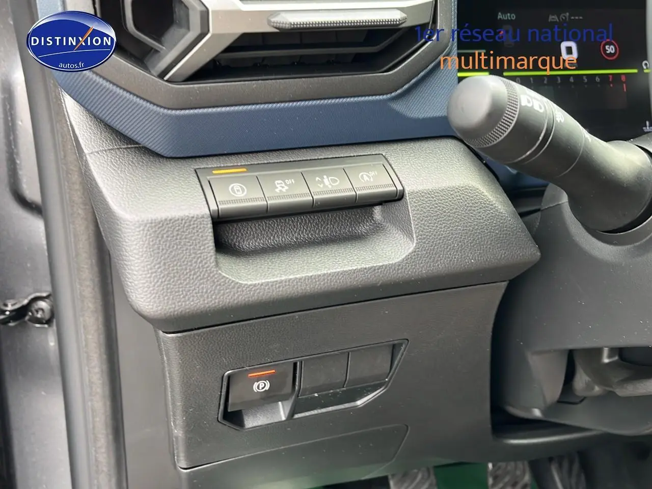 Détail intérieur côté gauche du tableau de bord gris avec commandes d'assistance et frein à main électrique du Dacia Duster 2025.