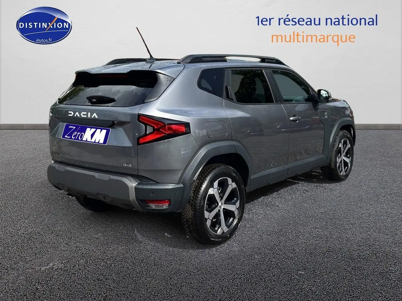 Dacia Duster gris schiste en 3/4 arrière droit avec barres de toit et jantes alu visibles.