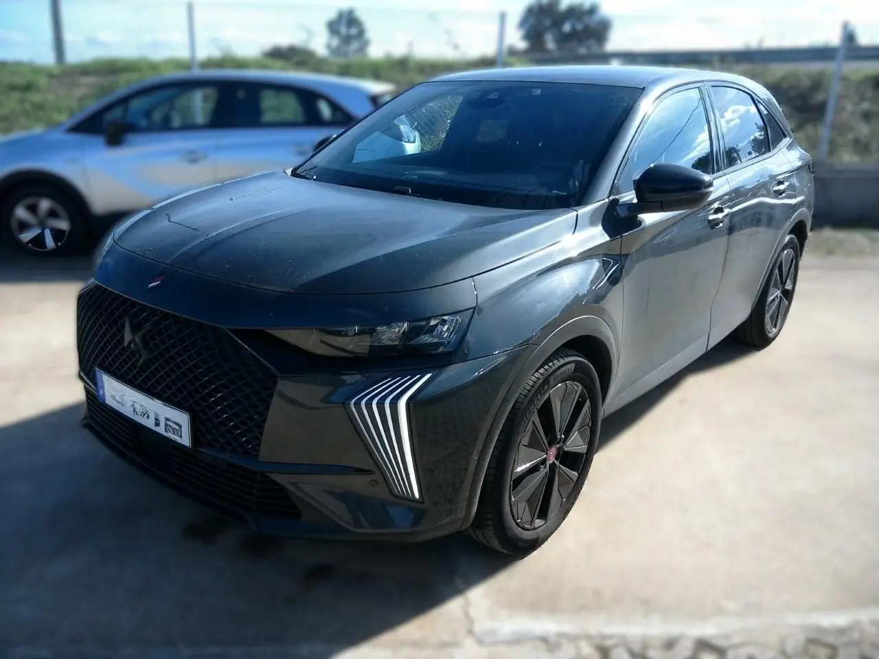 DS7 E-TENSE gris en 3/4 avant droit, avec calandre noire distinctive et feux LED verticaux marquants.