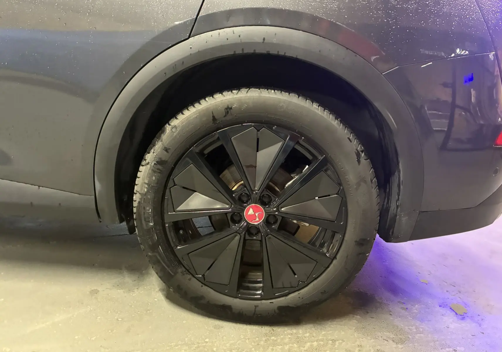 Gros plan sur la roue arrière droite du DS7 E-TENSE gris 2024 avec jante noire au design géométrique et logo rouge central.