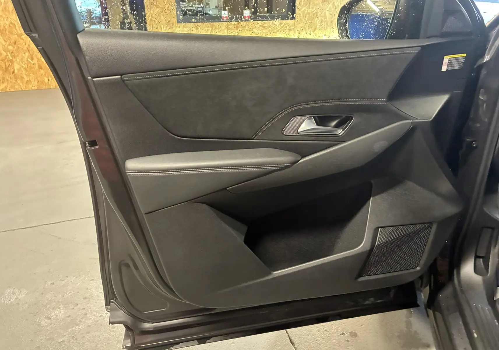 Vue intérieure côté gauche de la porte avant gris foncé du DS7 E-TENSE avec garniture en cuir et insert tissu.