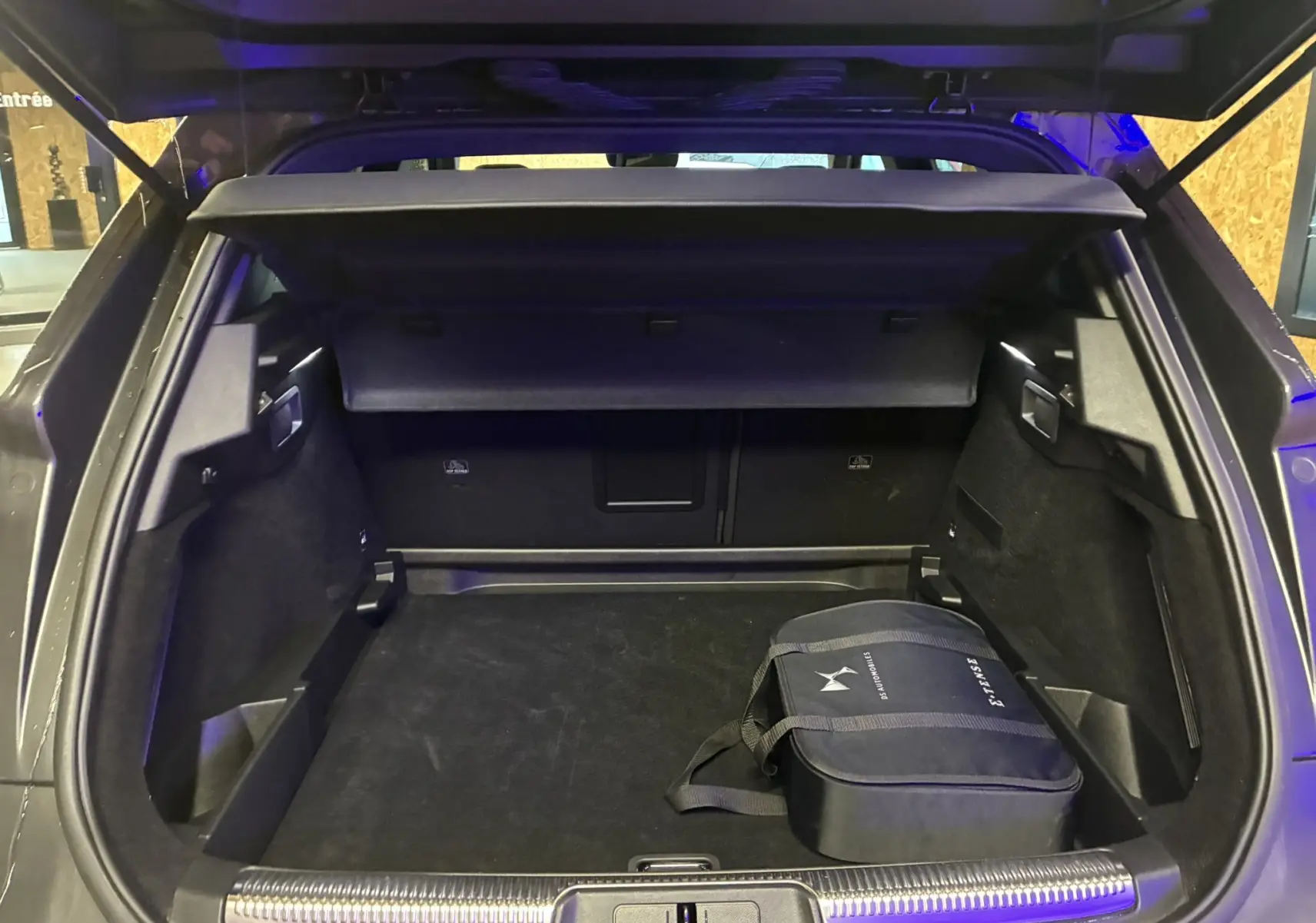 Vue arrière du coffre ouvert du DS7 E-TENSE gris 2024, avec sac de chargeur hybride visible à droite.